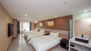 A hotel room with two beds, a TV, a desk, and a bathroom with a mirror and sink.