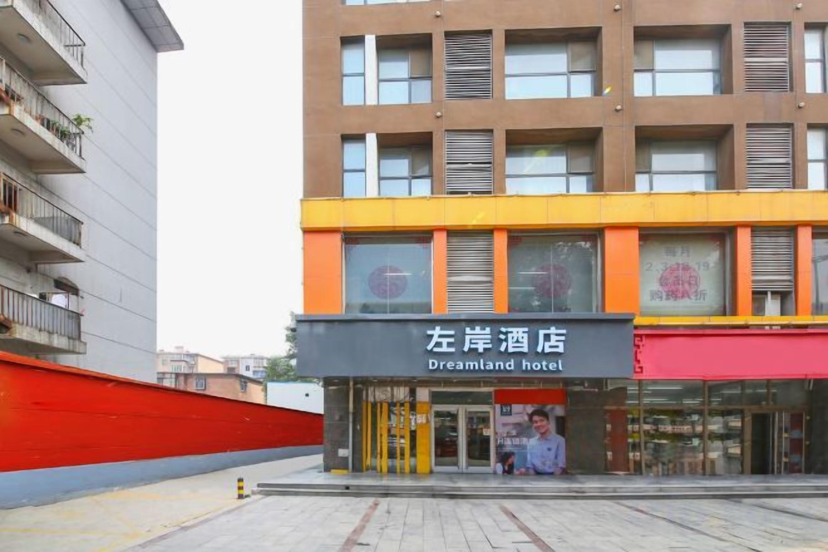A hotel with a sign reading 'Dreamland Hotel' in front of a modern building with multiple windows and balconies.