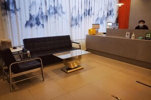 Un espace d’accueil comprenant un canapé, une table basse, un fauteuil et un comptoir de réception.