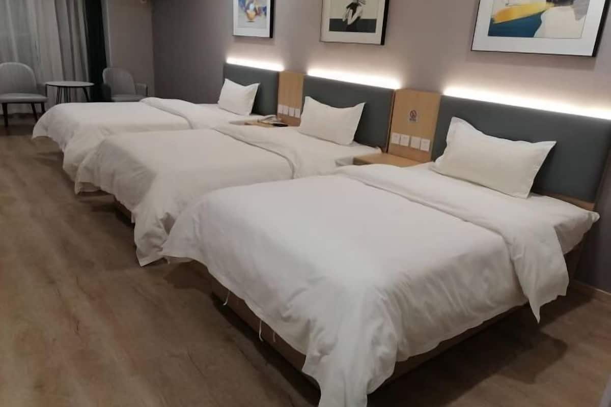 Une chambre d’hôtel avec trois lits, une petite table ronde et des chaises.