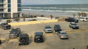 Un estacionamiento con varios autos y un edificio de varios pisos y balcones.