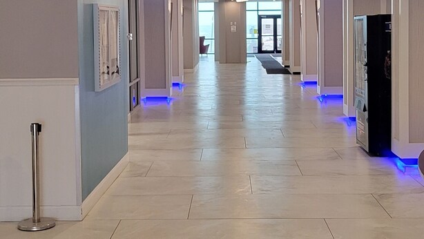 Un pasillo de hotel con señalización de salida clara, iluminación moderna y suelo de baldosas.