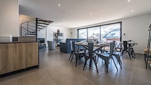 Een moderne keuken met een houten aanrecht, een spiltrap en een eethoek met zwarte stoelen en een groot raam.