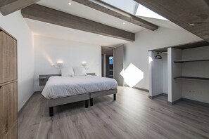 Une chambre à coucher moderne avec une lucarne, un lit, une armoire et un dressing.