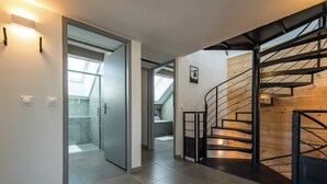 Ein modernes Interieur mit einer Treppe, einer Glastür zu einer Duschkabine und Blick zum Himmel durch ein Oberlicht.