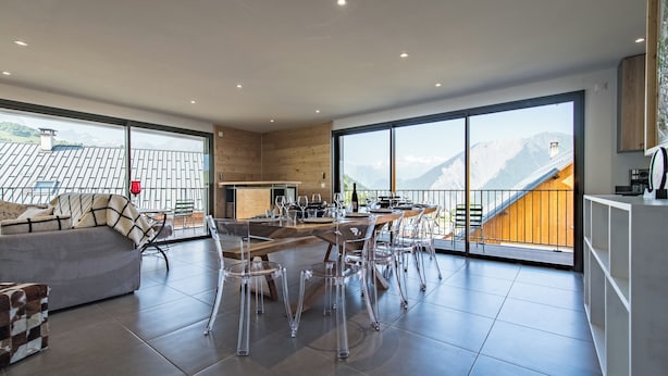 Ein modernes Wohnzimmer mit Essbereich, großen Fenstern und Bergblick.