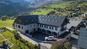 Ein großes Gebäude mit Innenhof, umgeben von grünen Feldern und Bergen im Hintergrund.
