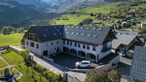 A large building with a sloped roof, a courtyard, and a mountain in the background.