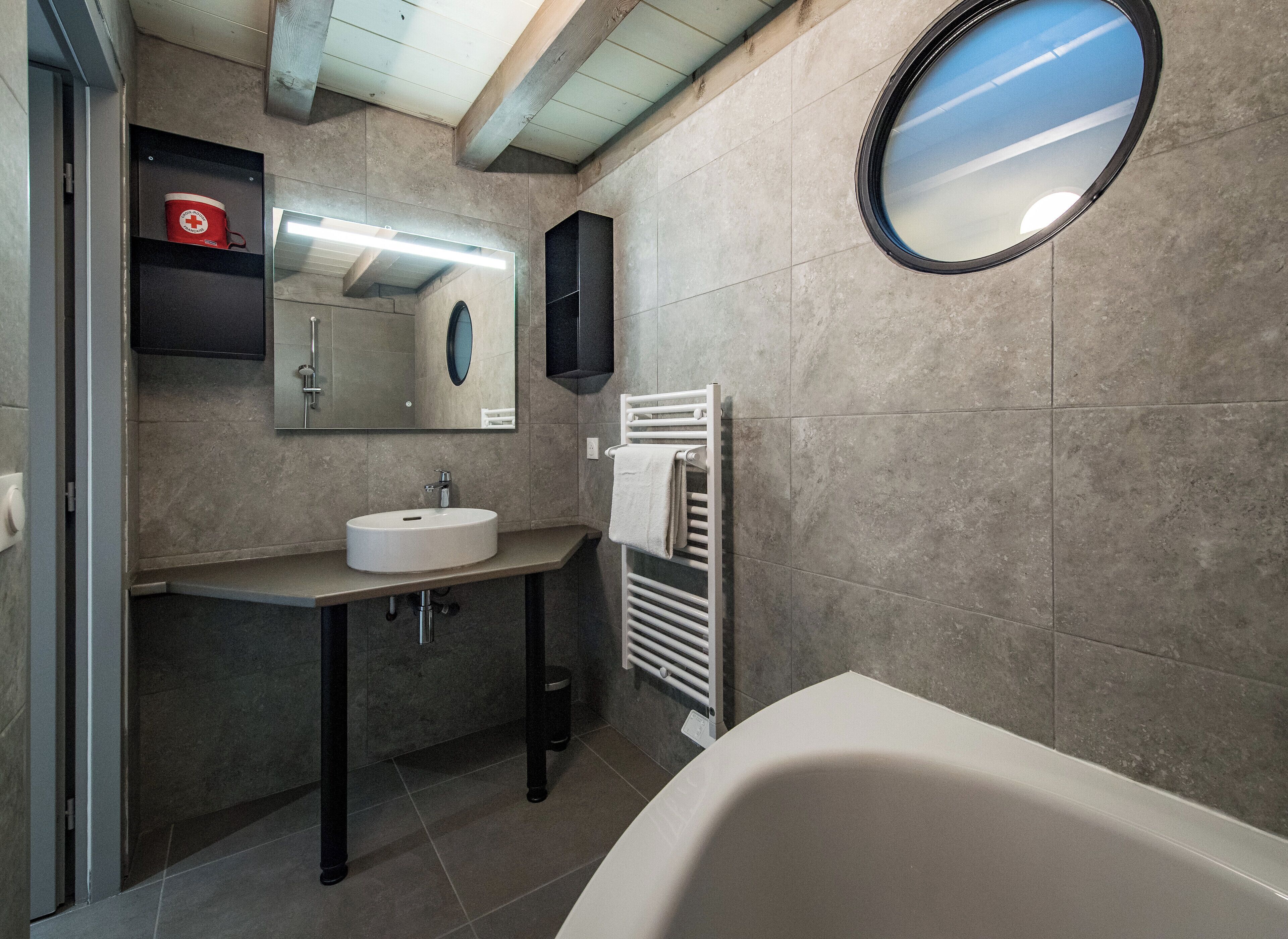 Un baño moderno con lavamanos, espejo y bañera blancos.