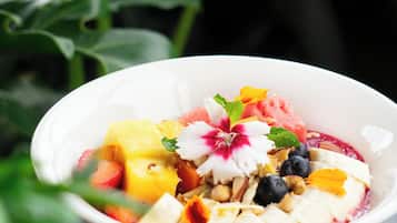Una ciotola bianca con una coppetta di frutta e yogurt su un fondo scuro.