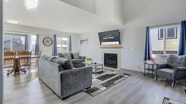 A modern living room with a grey sofa, a fireplace, a television, and a dining area with wooden chairs and a table. - Peaceful Family Retreat w/ Pool Near Colorado Springs & Airport (Colorado Springs)