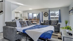 A modern bedroom with a bed, two grey sofas, a dining area, and a kitchen in the background. - Peaceful Family Retreat w/ Pool Near Colorado Springs & Airport (Colorado Springs)