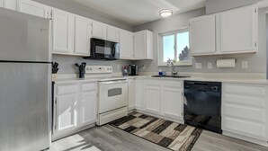 A modern kitchen with white cabinets, stainless steel appliances, and a patterned rug. - Peaceful Family Retreat w/ Pool Near Colorado Springs & Airport (Colorado Springs)