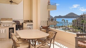 Ein Balkon mit Tisch und Stühlen, einem Grill und Blick auf das Meer und die Berge.