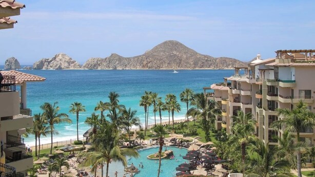 Ein Resort mit Pool, Palmen und Blick auf Meer und Berge.