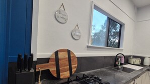 Een keuken met een gasfornuis, een houten snijplank en twee borden aan de muur.