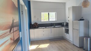 Een moderne keuken met witte kasten, een roestvrijstalen koelkast en een houten vloer.