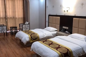 Ein Hotelzimmer mit zwei Betten, einem kleinen Tisch, einem Stuhl und einem Nachttisch.
