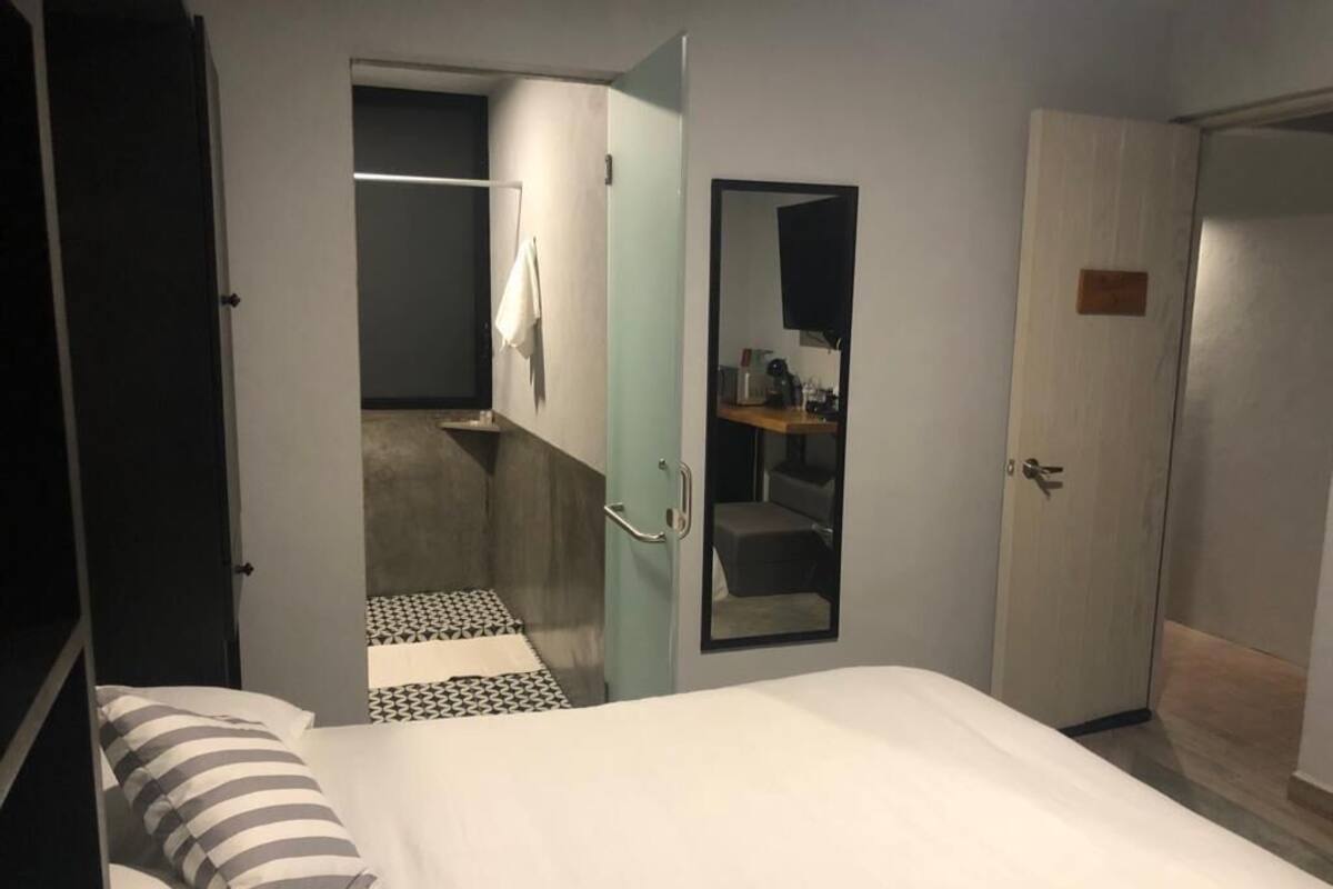 Ein Hotelzimmer mit Bett, Spiegel, Kleiderschrank und einem kleinen Badebereich.
