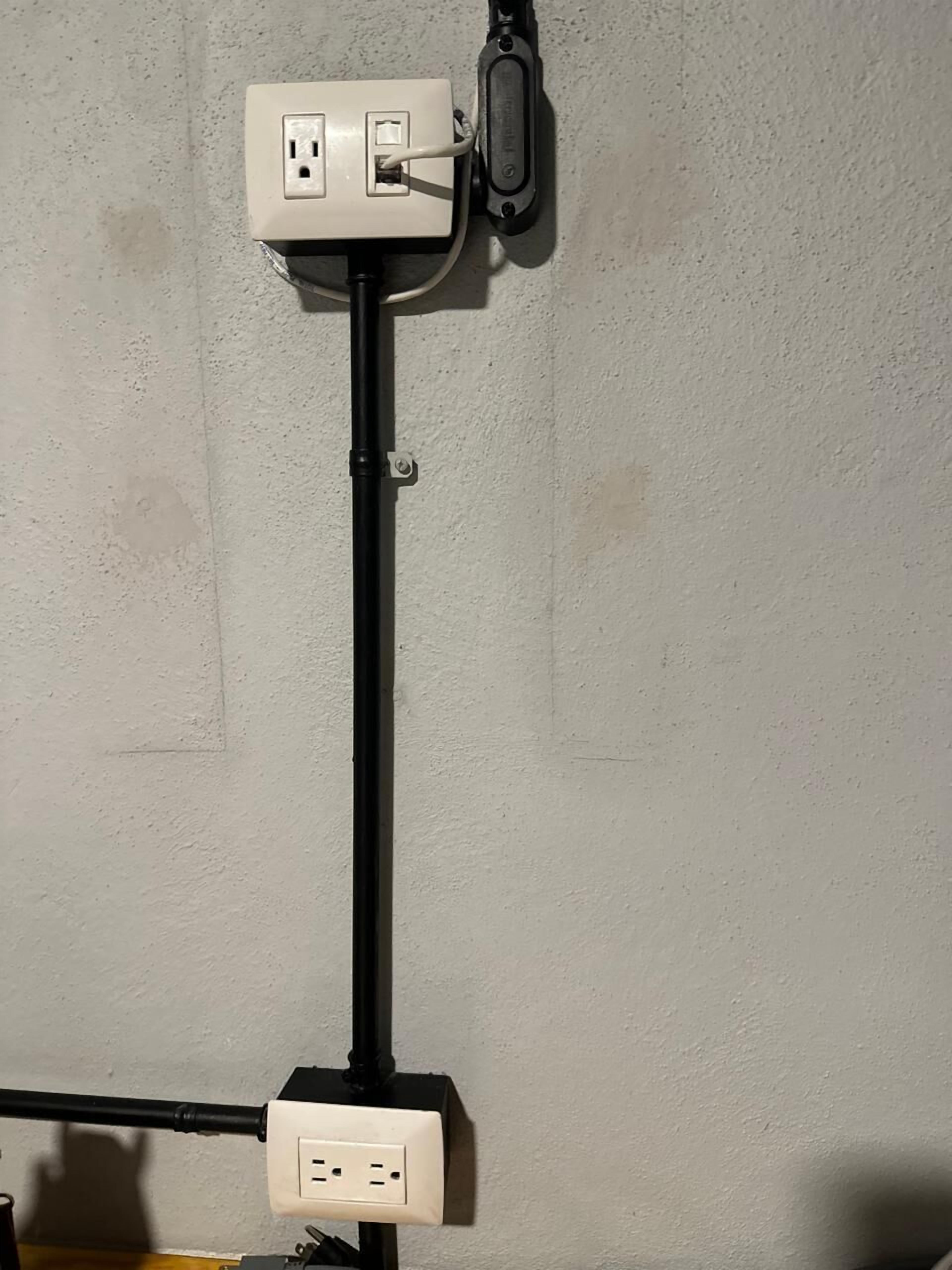 A wall-mounted electrical outlet with a cable connected to a device.