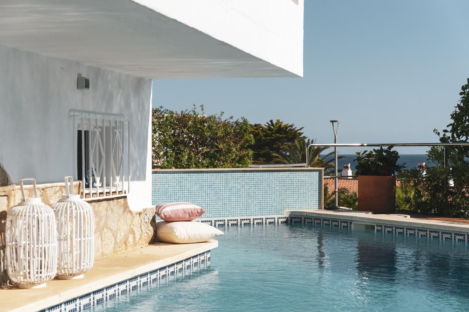 A pool area with a clear view of the sea, a tiled wall, and decorative items.