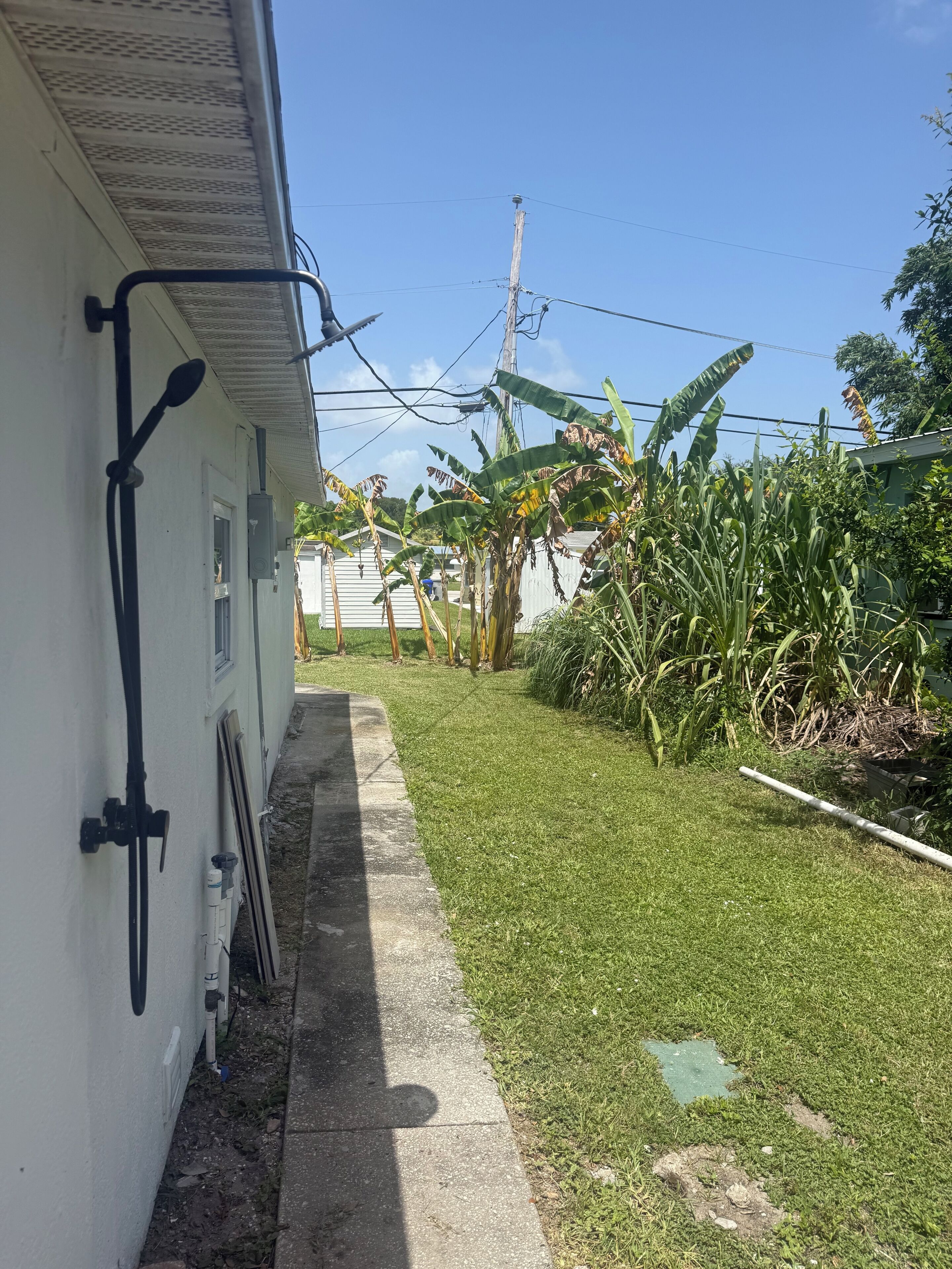 A narrow pathway leading to a white building with a metal railing on the left.