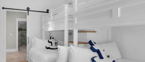 Ein modernes Schlafzimmer mit Etagenbett, klappbarem Schreibtisch und Dusche.