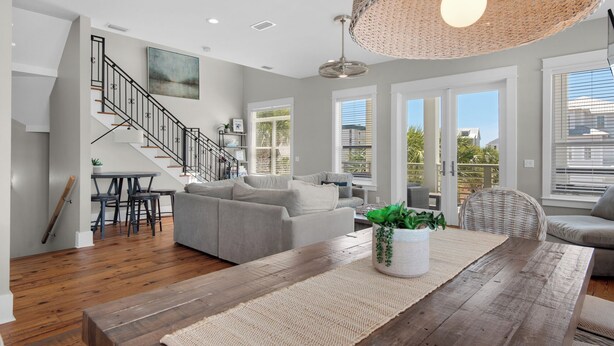 Una sala de estar moderna con una escalera, un comedor y ventanas amplias.