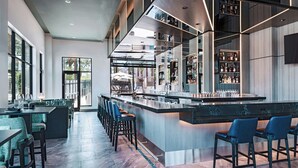 Un espace bar moderne avec un long comptoir, des tabourets de bar et un présentoir à bouteilles de vin.