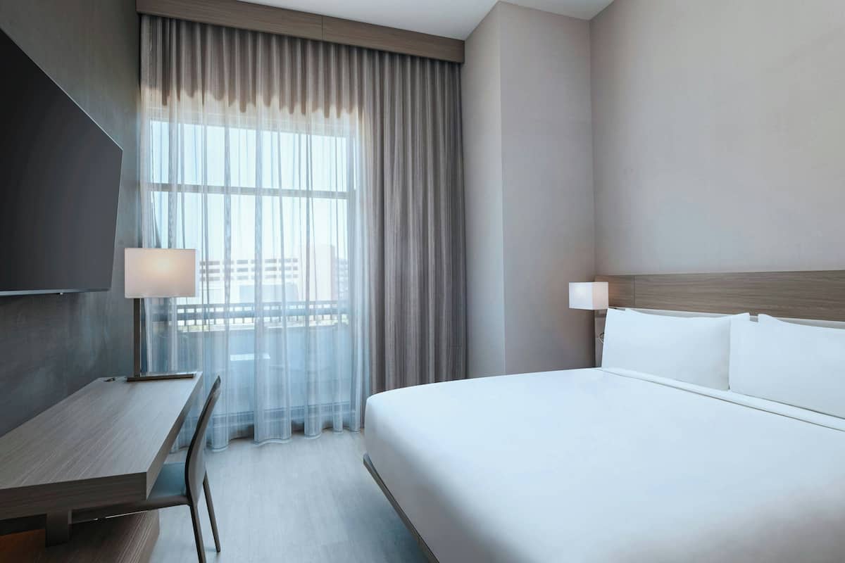 Una camera d'albergo con un letto, una scrivania, una sedia e una televisione.