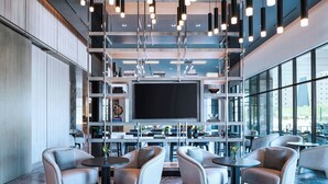 A modern interior with seating, a large flat-screen TV, and a view through large windows. - AC Hotel by Marriott Las Vegas Symphony Park (Las Vegas)