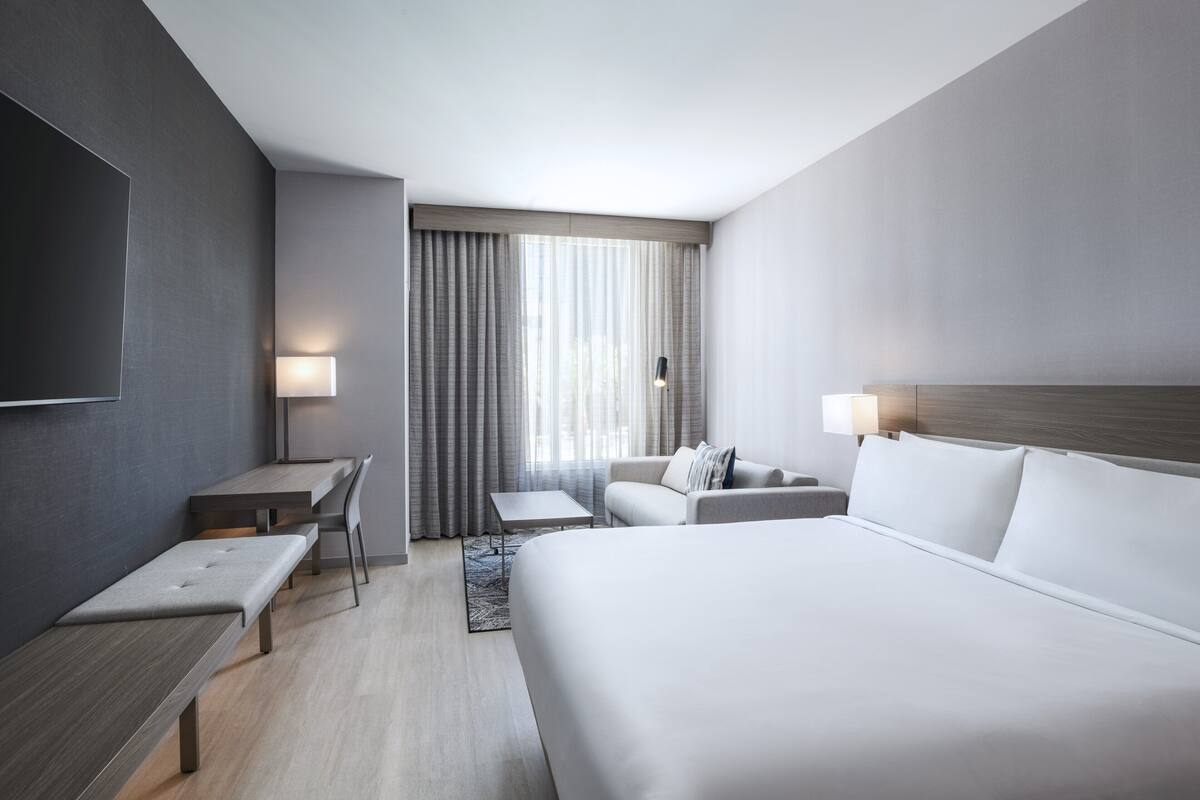 Una camera d'albergo moderna con un letto grande, una scrivania, una sedia e un divano.