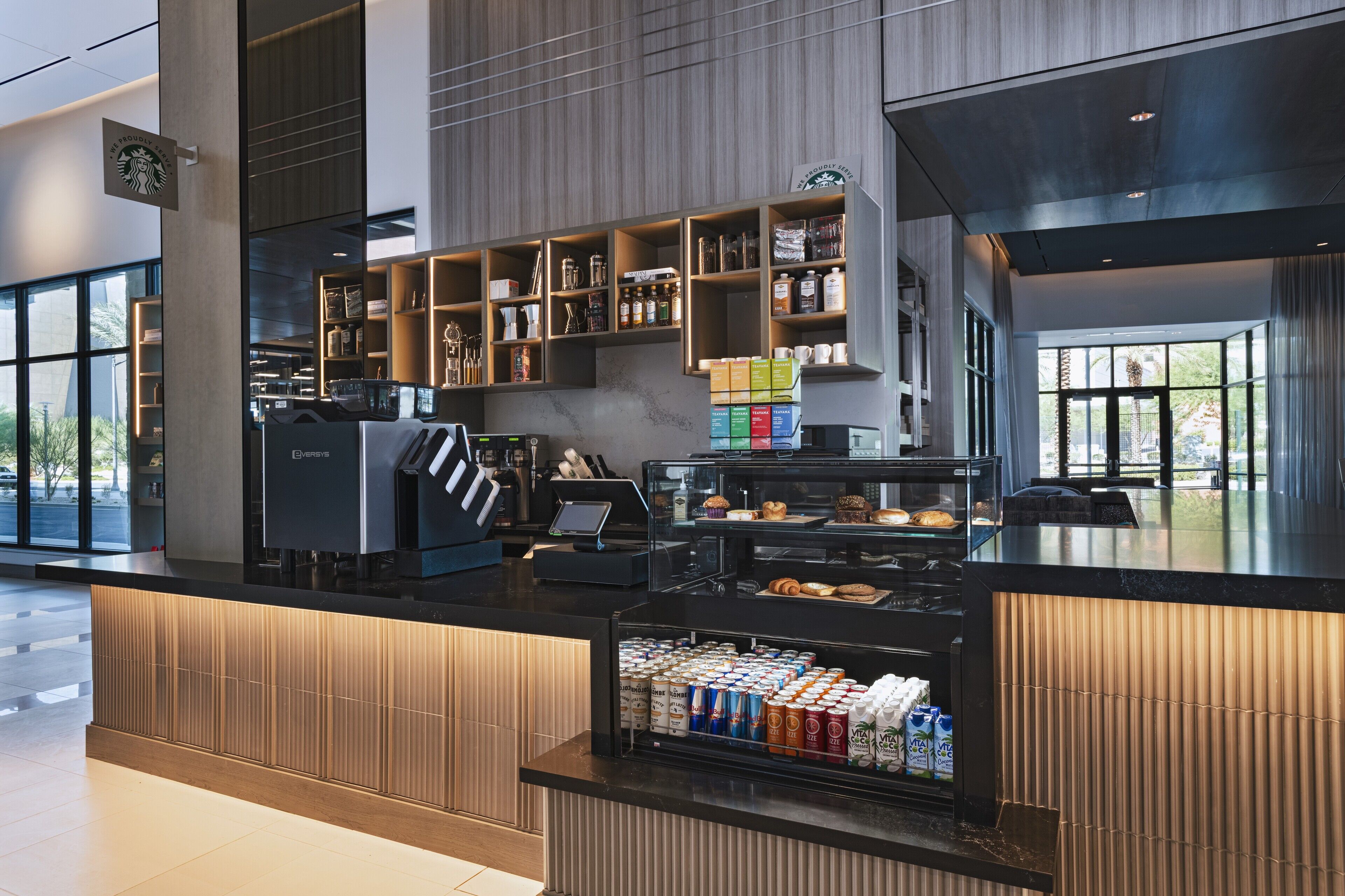 Un Starbucks moderne doté d’un terminal en libre-service, proposant une variété de produits de boulangerie et un choix de boissons.