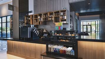 A modern Starbucks with a self-service kiosk, a variety of baked goods, and a selection of beverages.