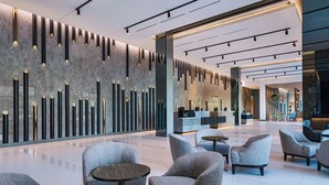 A modern lobby with seating, a reception desk, and a decorative wall. - AC Hotel by Marriott Las Vegas Symphony Park (Las Vegas)