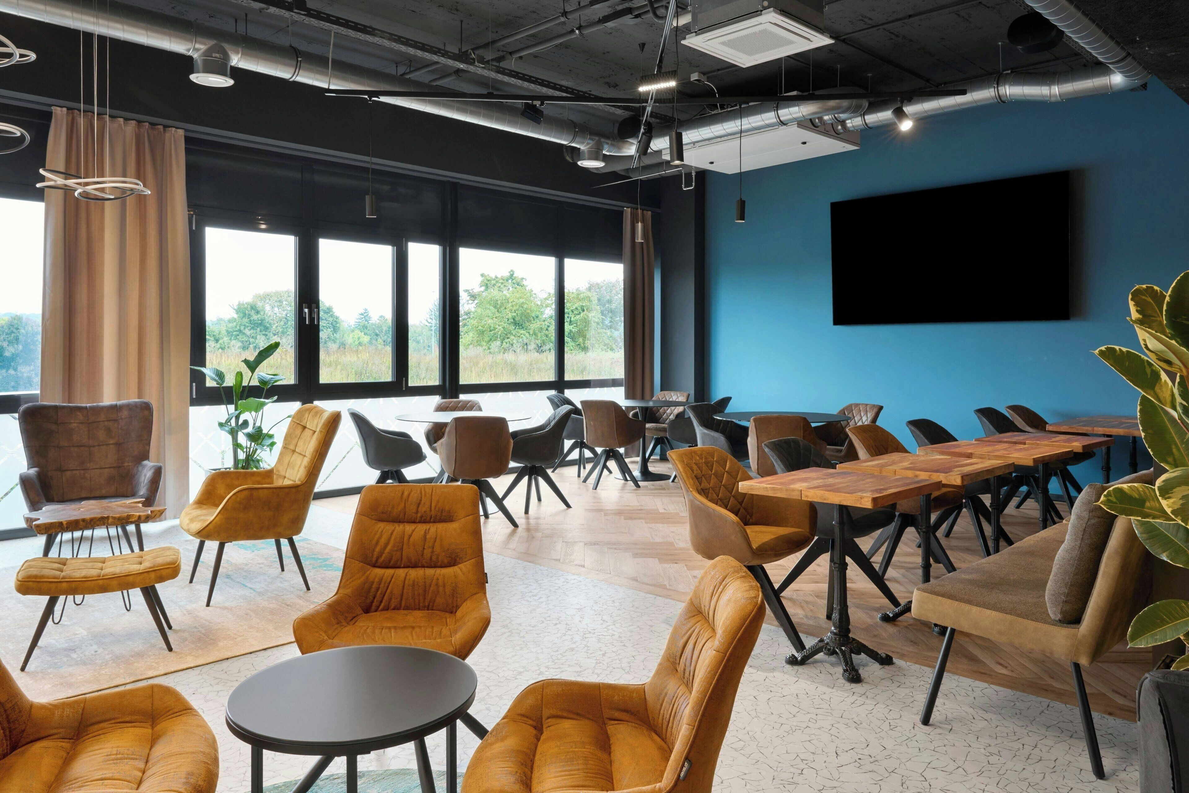 A conference room with large windows, modern furniture, and a flat-screen TV.