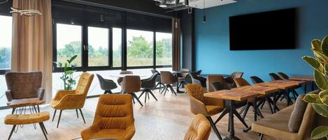 A conference room with large windows, modern furniture, and a flat-screen TV.