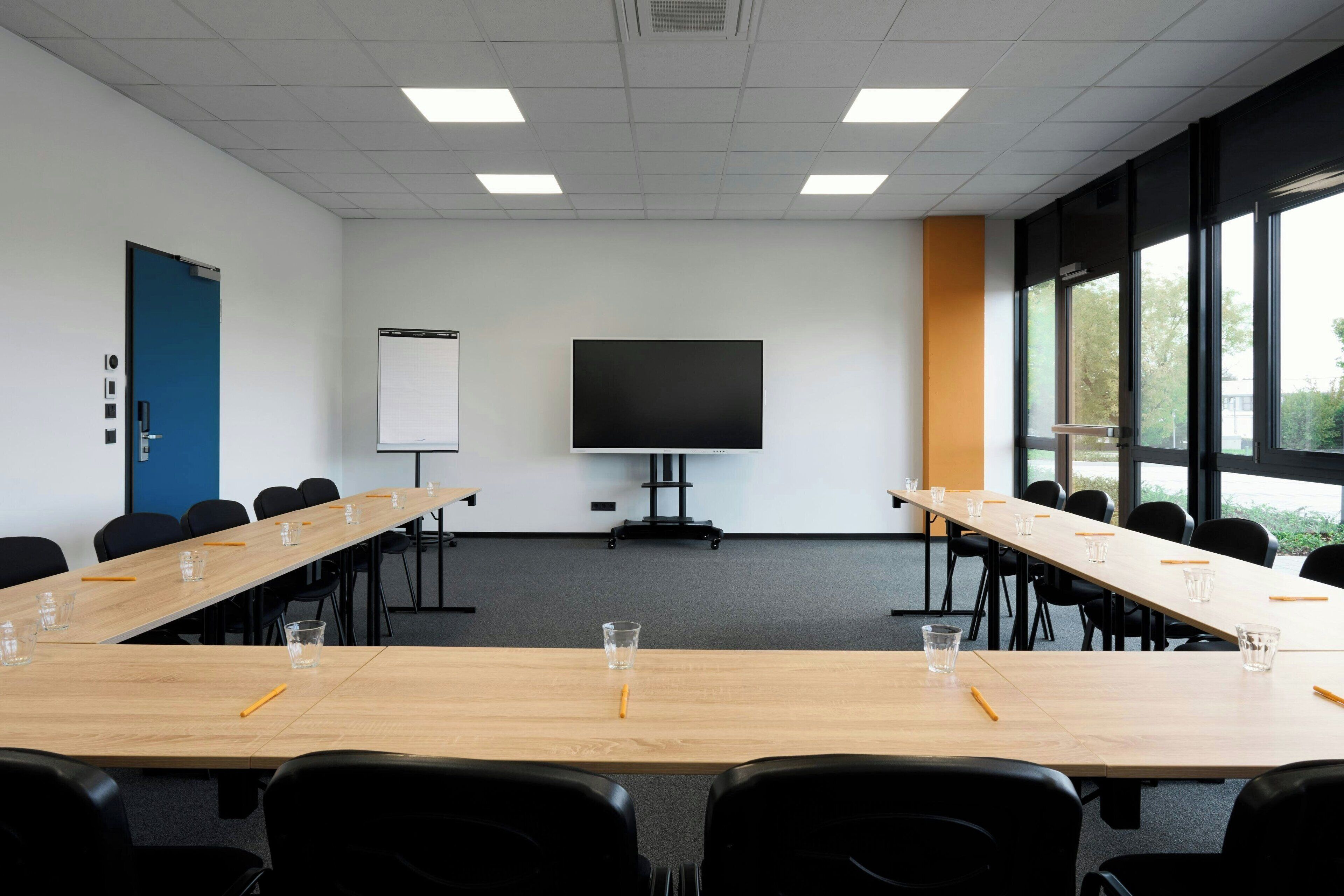A conference room with a long table, chairs, a projector screen, and a whiteboard.