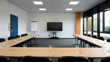 A conference room with a long table, chairs, a projector screen, and a whiteboard.