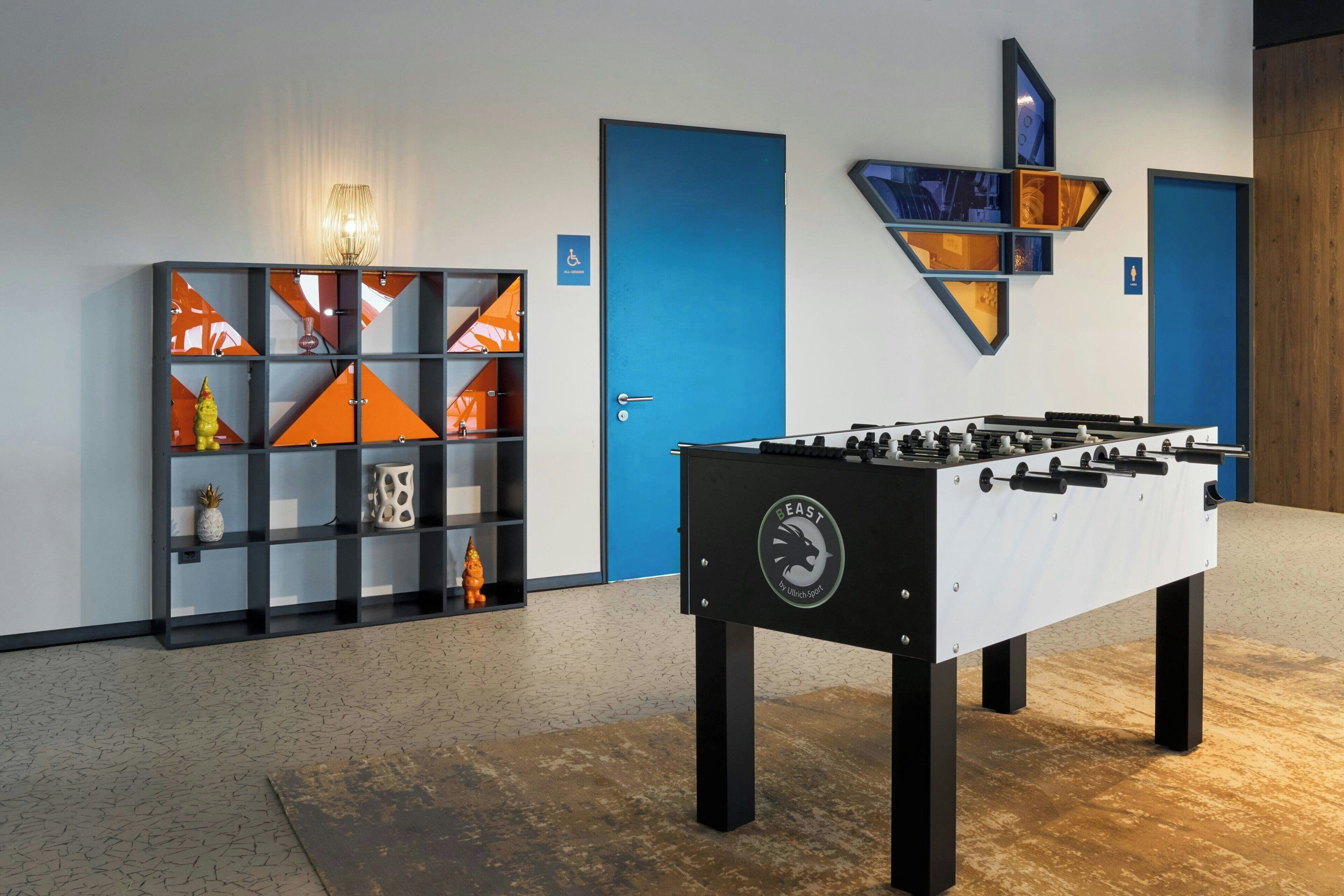 A modern room with a foosball table, a decorative cabinet, and blue doors.