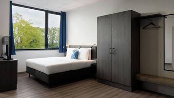 Ein modernes Schlafzimmer mit einem Bett, einem Kleiderschrank und einem Fernseher auf einer Kommode.