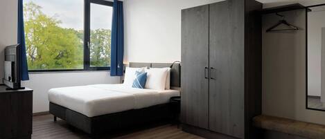 A modern bedroom with a bed, wardrobe, and a television on a dresser.