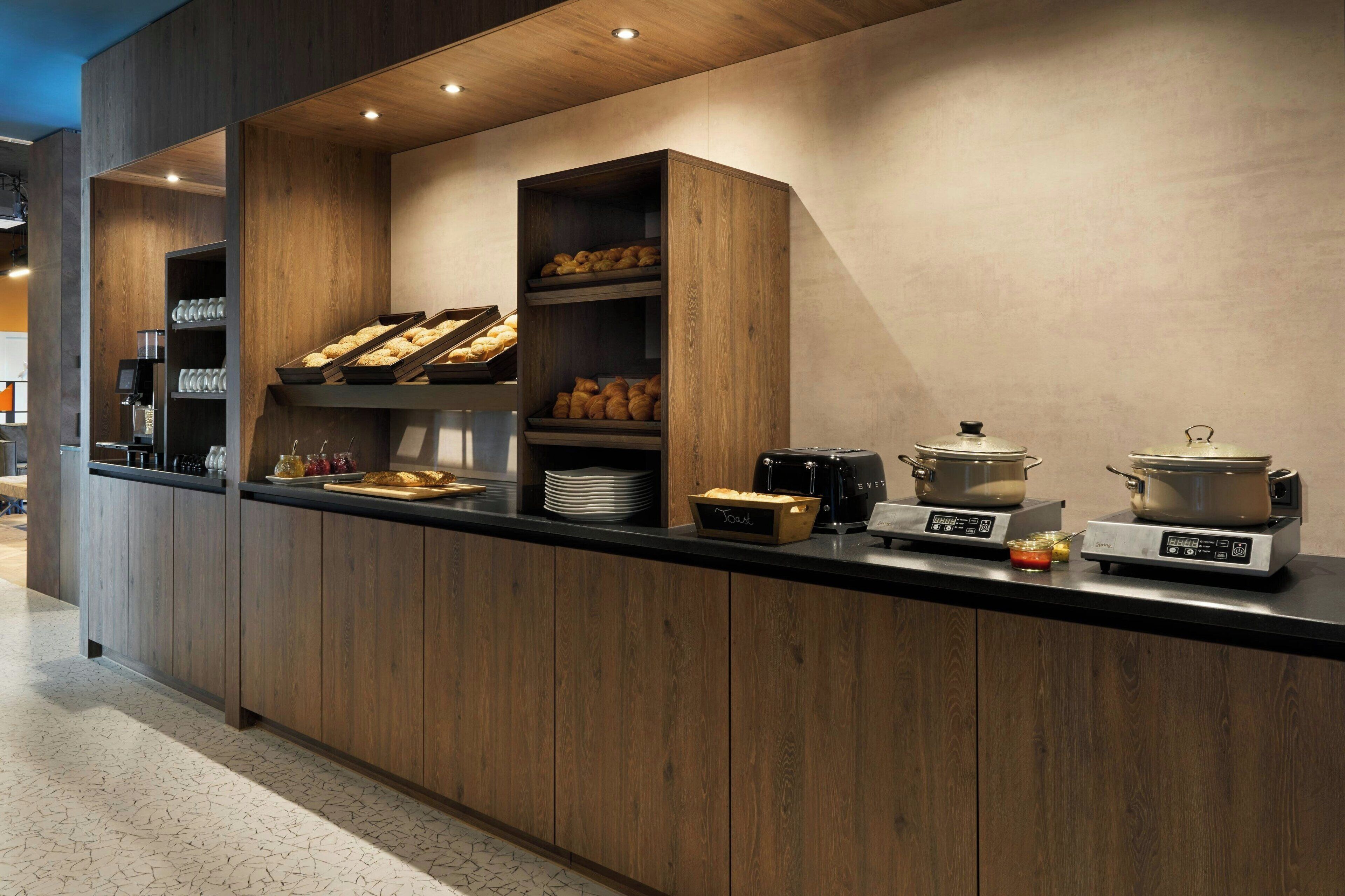 Une cuisine moderne avec des meubles en bois, un plan de travail noir et divers appareils, notamment une machine à café, un grille-pain et une bouilloire.