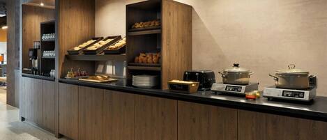 A modern kitchen with wooden cabinets, a black countertop, and various appliances including a coffee machine, a toaster, and a kettle.