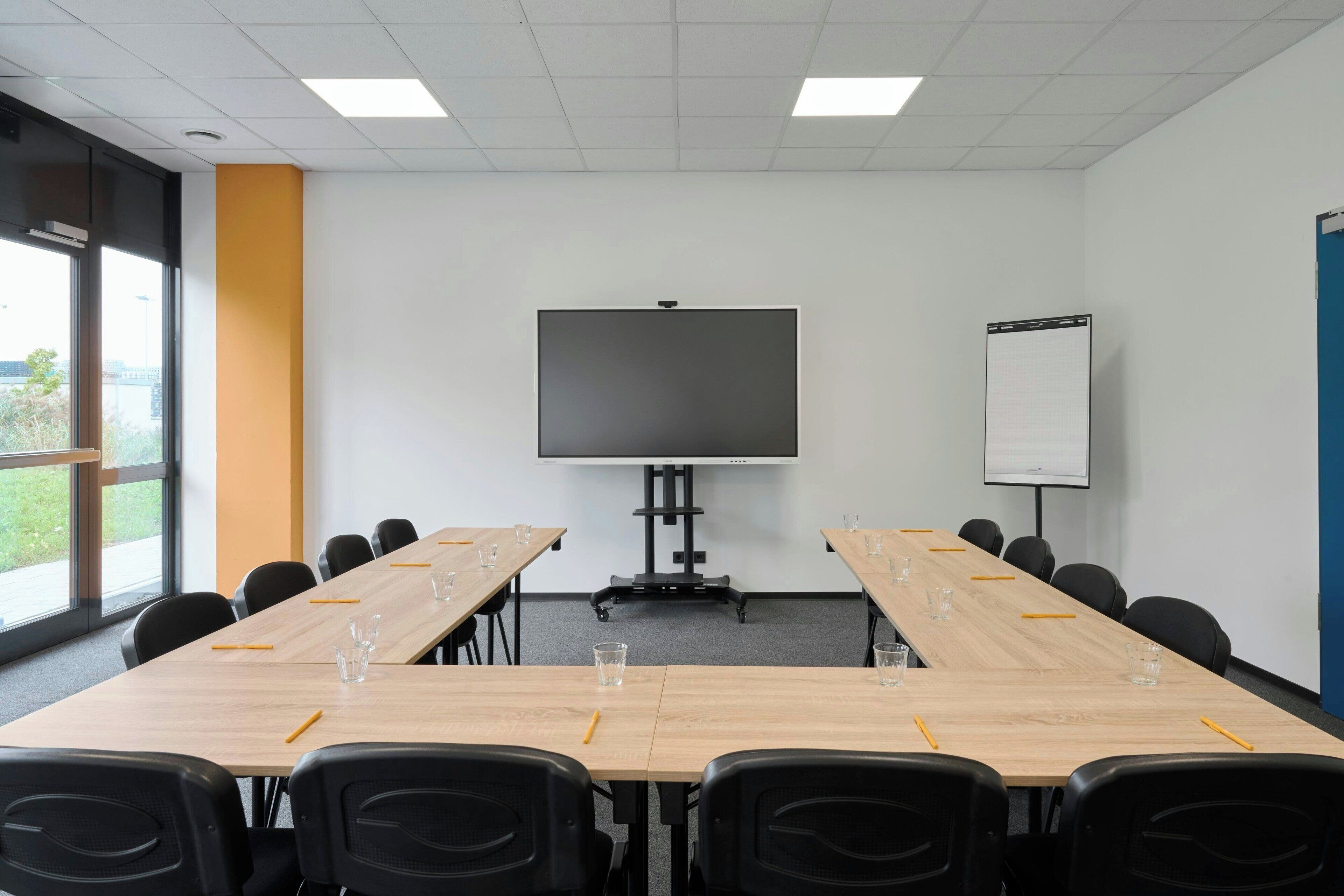 A conference room with a large table, chairs, a projector screen, and a whiteboard.