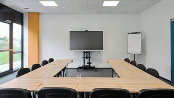A conference room with a large table, chairs, a projector screen, and a whiteboard.