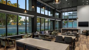 Un espacio interior moderno con un amplio comedor, arreglos de asientos y grandes ventanas con vistas al exterior.