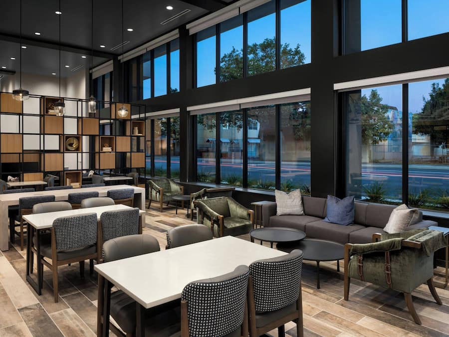 A modern interior with a seating area, tables, and a large window overlooking a street.