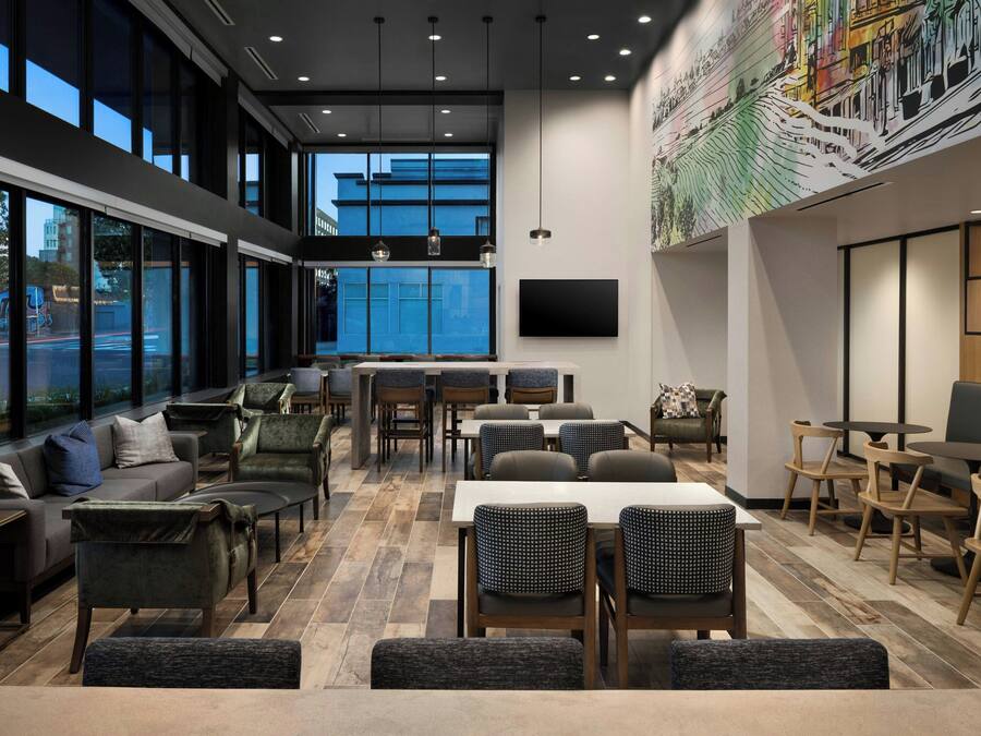 A modern restaurant with high ceilings, large windows, and a variety of seating options including tables and chairs.
