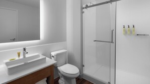 A modern bathroom with a white sink, toilet, and glass shower enclosure.
